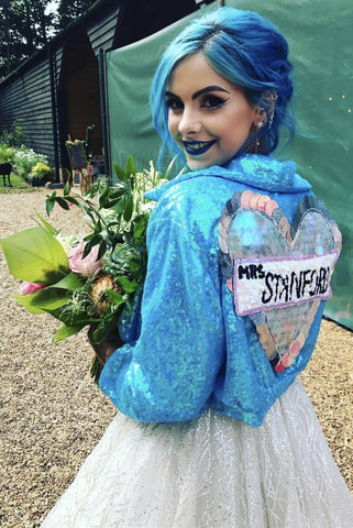 bride with blue hair wears customised Isolated Heroes sequin biker jacket with her wedding dress 