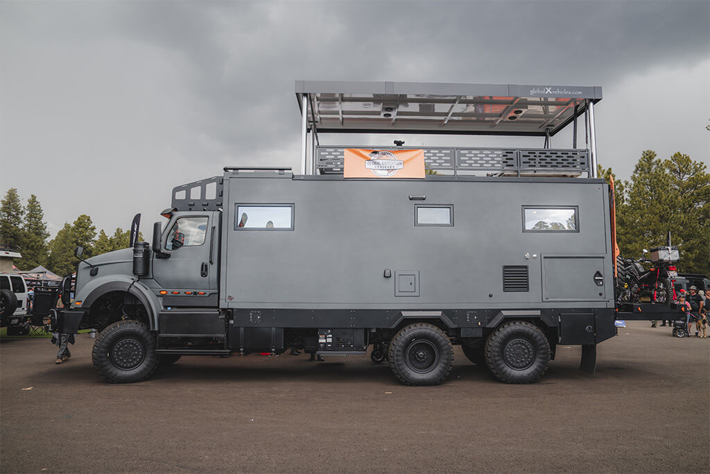 enormous expedition vehicle with motorcycle hauler on back