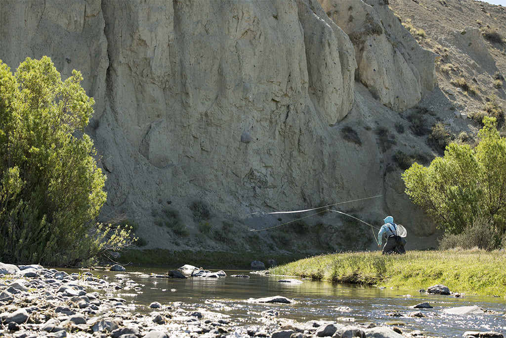 A fly fisherman casts into the river from the shore