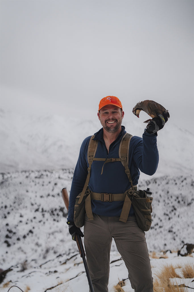Travis Warren smiles as he shows the camera a chukar he's harvested