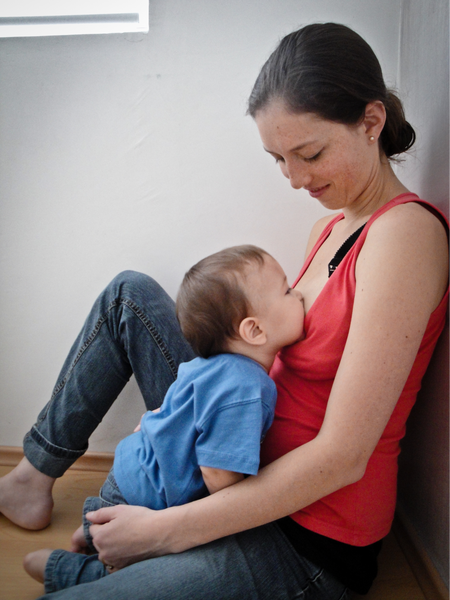 Mother breastfeeding child sitting on the floor
