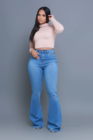 Swank girl wearing stretchy flare jeans with a beige long sleeve cropped top