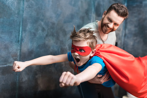 dad holding son dressed as as superhero