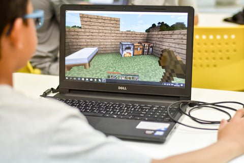 boy playing Minecraft on laptop