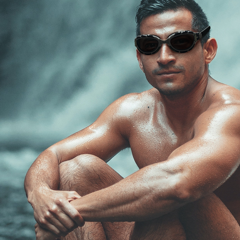 Male swimmer sitting down and wearing a pair of black swimming goggles