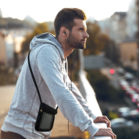 Male traveler on top of a parking structure with a passport holder around his neck