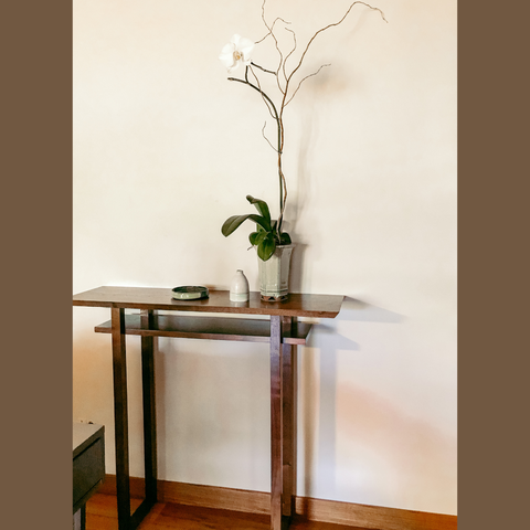 a custom classic console table in walnut with a tall orchid display.
