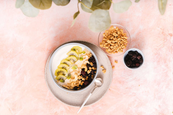 A smoothie bowl with fruit and cashews.