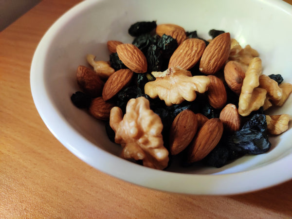A bowl of walnuts, almonds, and prunes.
