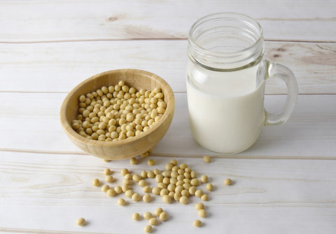 Soybeans and soy milk on a white table.