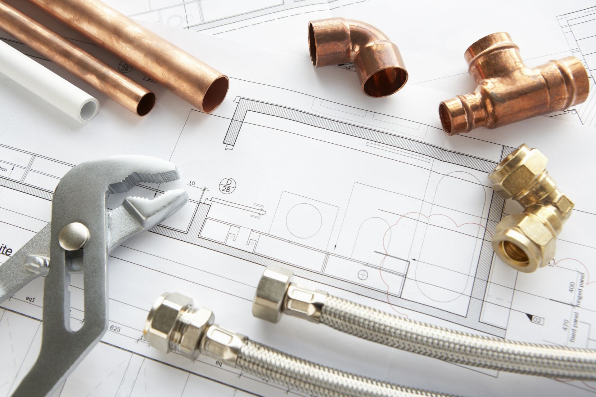 Several types of pipe fittings atop a printed blueprint