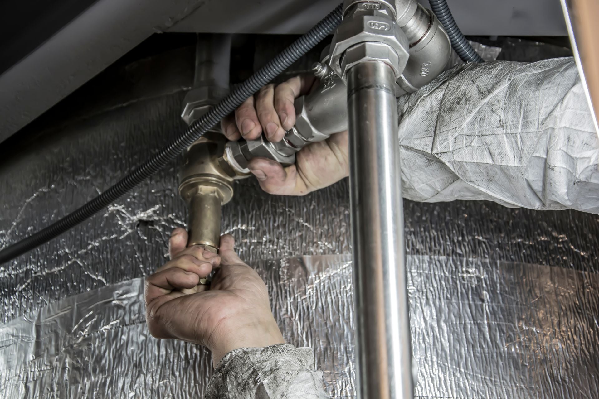 A person installing pipe fittings to a connecting pipe in a plumbing system