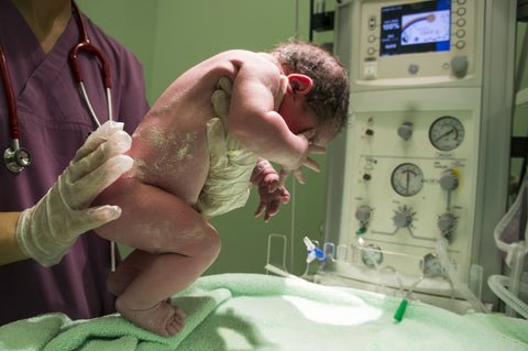 Hebamme untersucht neugeborenes Baby