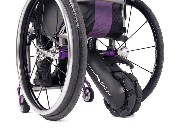 A photograph of a manual wheelchair with a power assist device attached