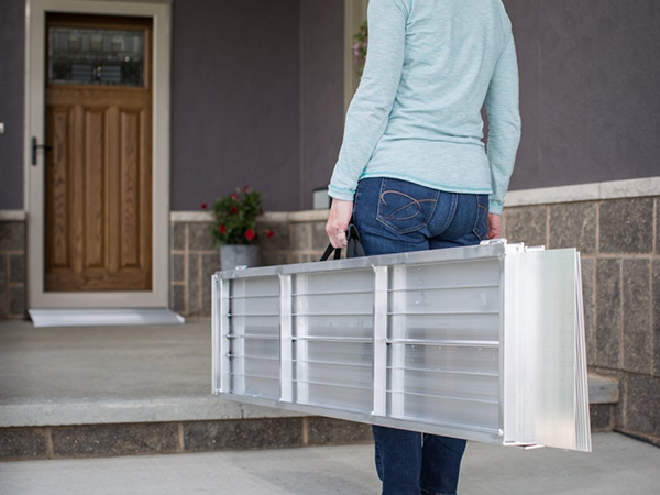 person carrying portable wheelchair ramp inside