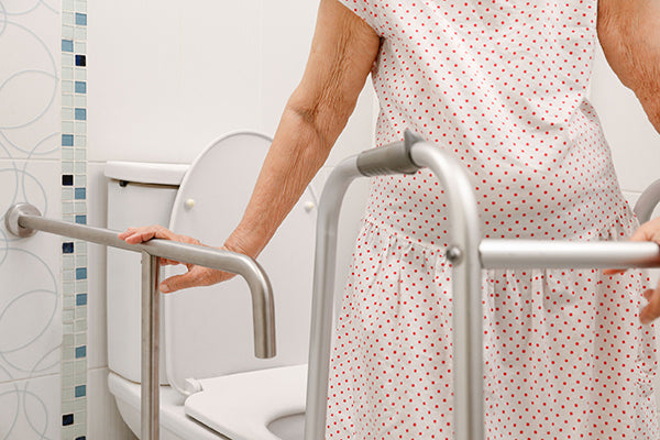 elderly woman using grab bars near the toilet