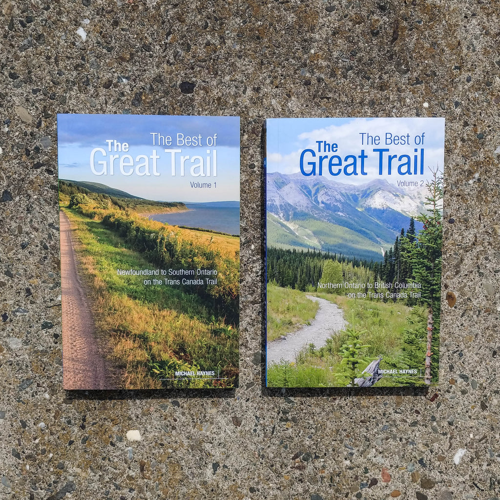Photo of two books lying on a smooth, speckled concrete surface. The books are Volume 1 and 2 of the The Best of the Great Trail.