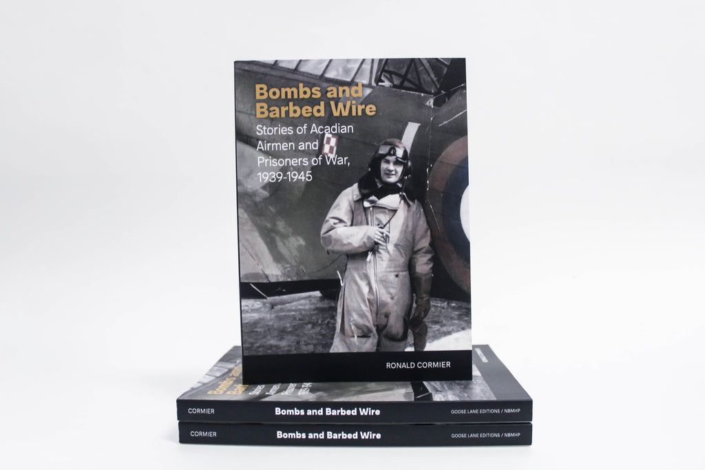 A copy of Bombs and Barbed Wire stands upright on a stack of two more copies of the book.