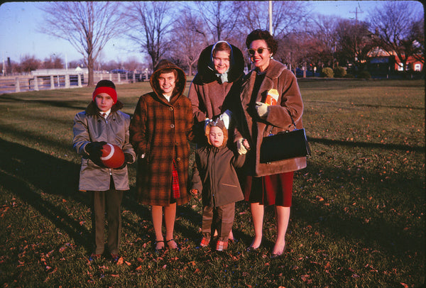 A photo of the four McKercher children and their mother, posed and smiling for the camera. The family stands outside in formal dress and winter coats.