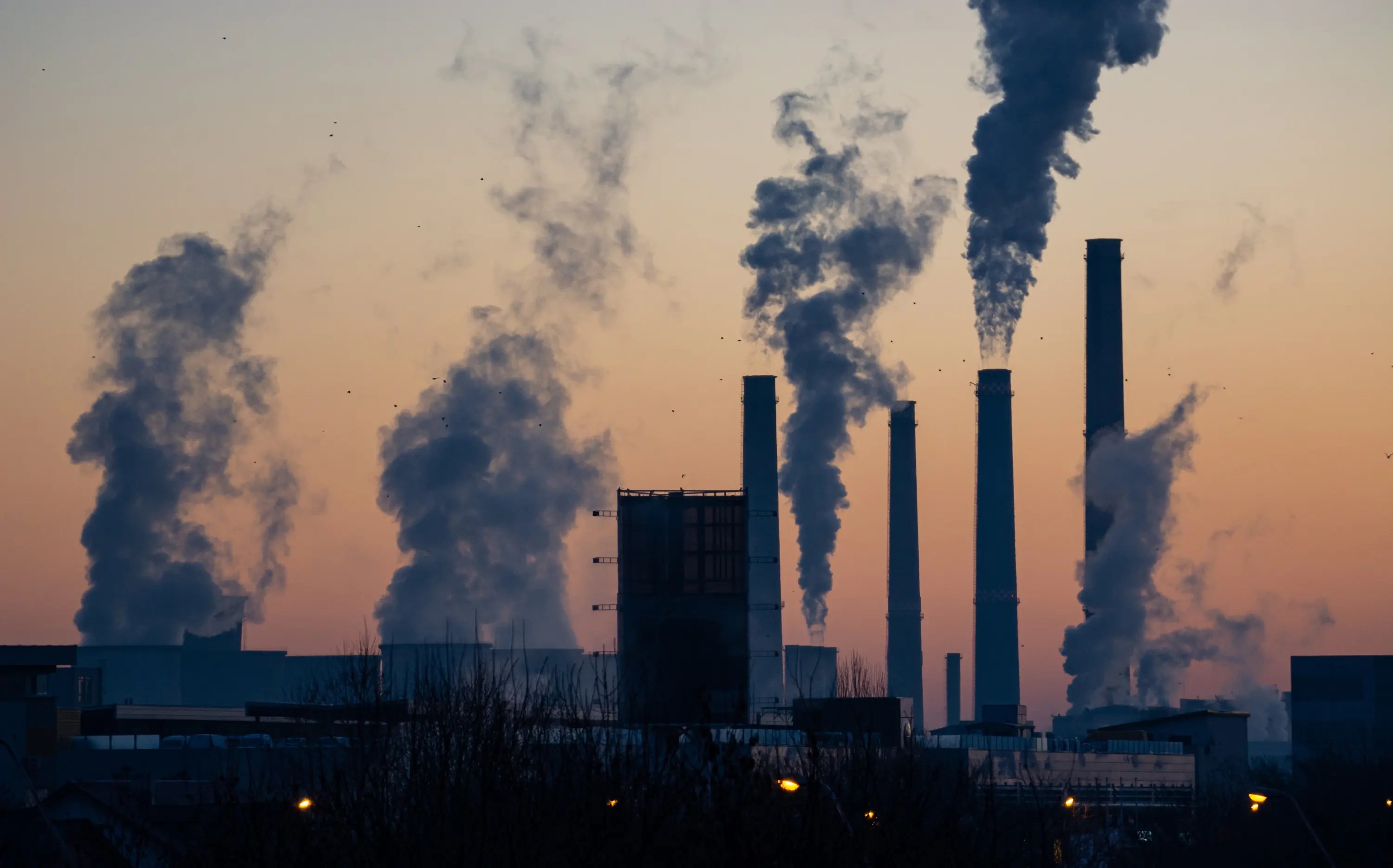 smoke billowing from a factory chimney at dusk