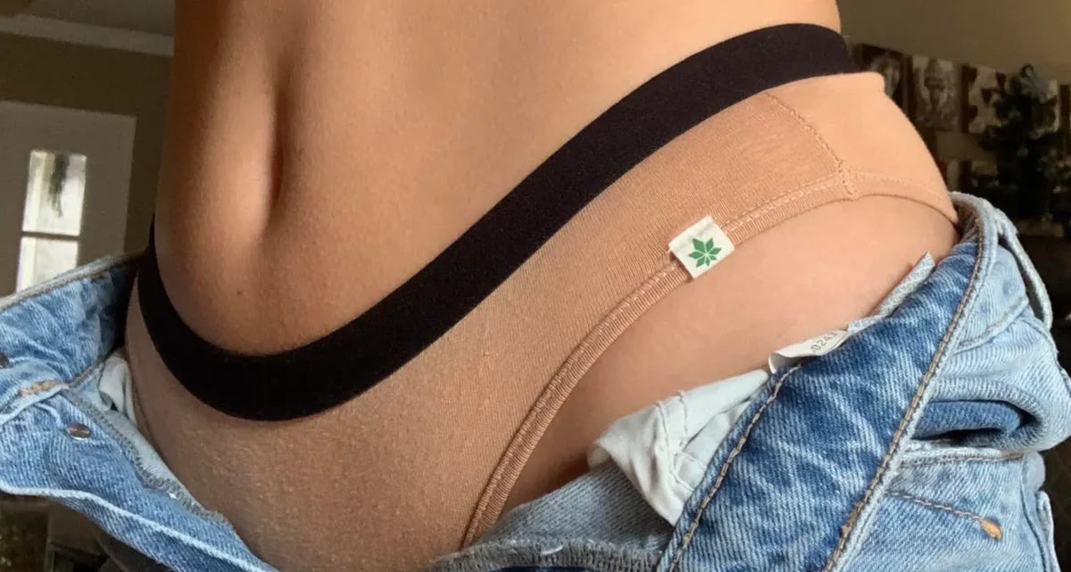 woman’s torso wearing nude underwear and unbuttoned denim jeans 