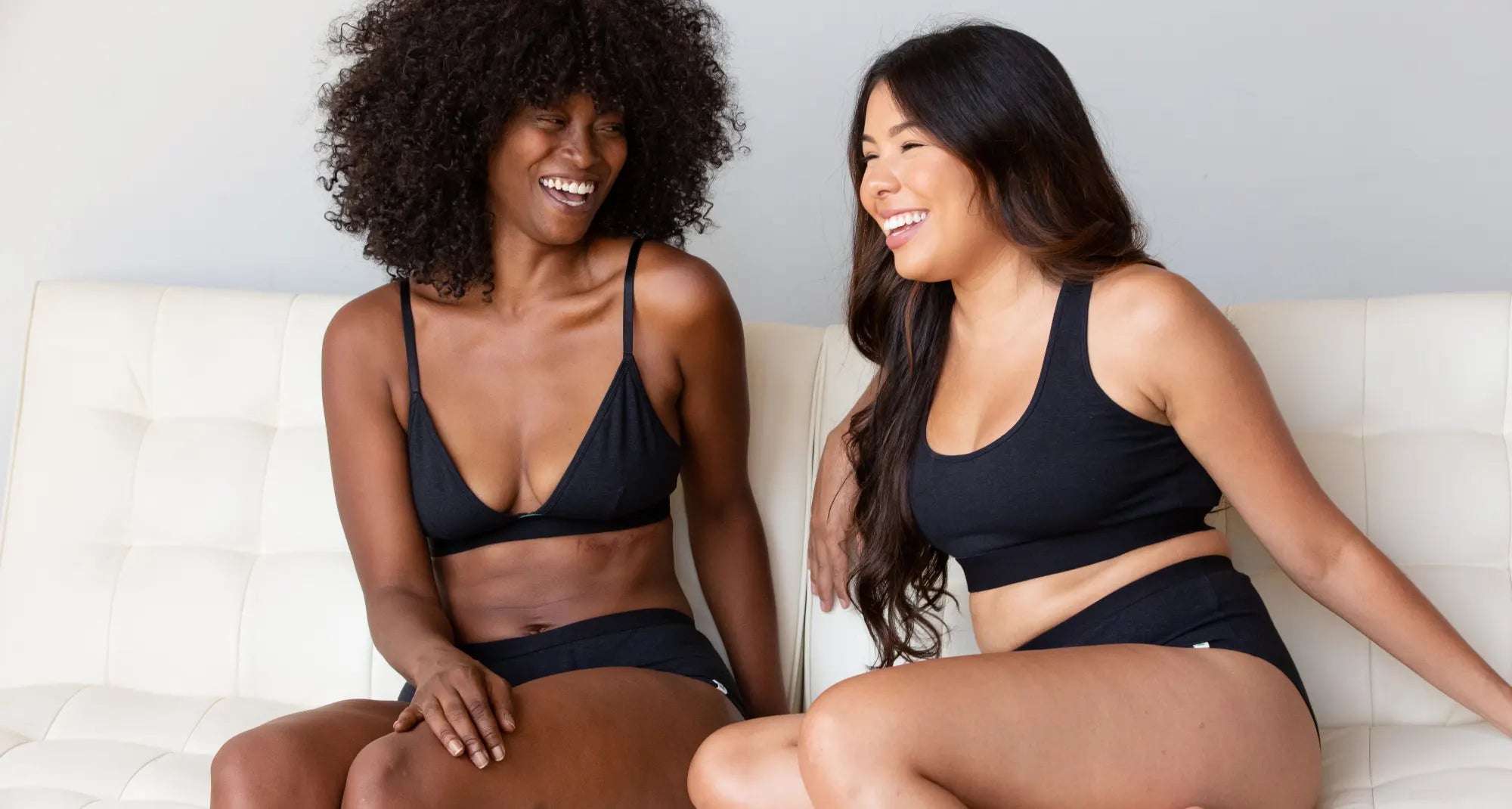  two women sitting on a couch laughing