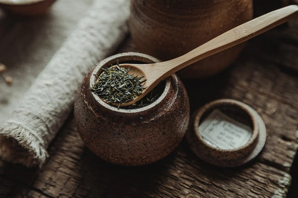  Green loose leaf tea in a small pot with a wooden spoon