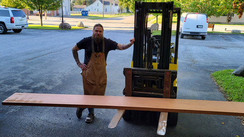 cheyenne posing with a forklift carrying a heavy mahogany board