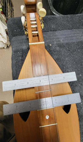 crooked fret on folkcraft dulcimer demostrated by placing rulers against the fret