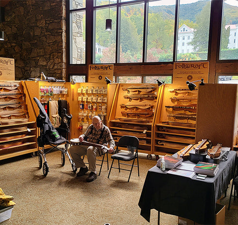 jim ash playing a lapjo in the folkcraft vending area at black mountain music festival