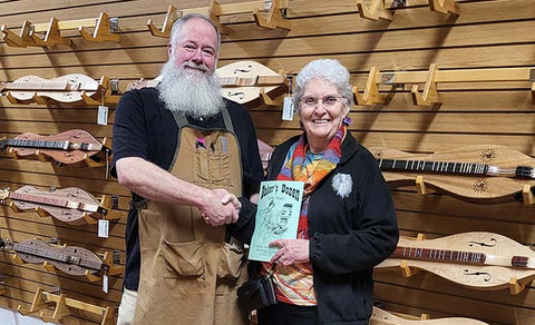 richard ash and shelley stevens shaking hands in the folkcraft instruments showroom