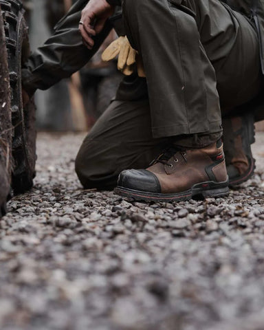 Man wearing safety boots for working near a vehicle on a farm