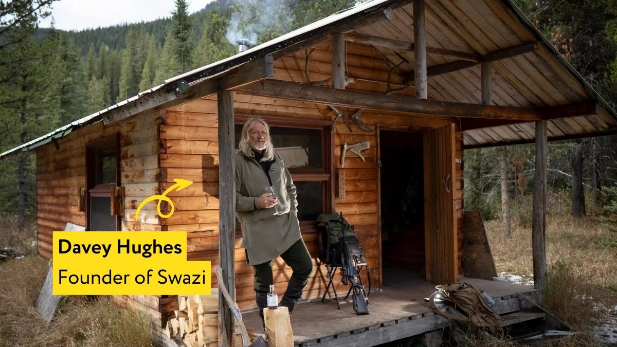 Davey Hughes wearing Swazi Clothing standing outside a wooden cabin in the countryside