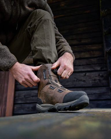 Person bending down to tie the Harkila Reidmar Mid 2.0 GTX Leather Boots in dark brown