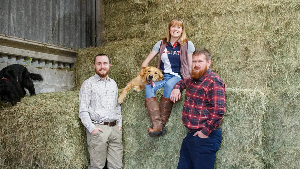 Matt, Sarah and Rob leaning next to a pile of hay.