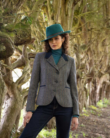 Woman wearing Jack Murphy Sasha Tweed Jacket with dark trousers standing outside in a wooded area