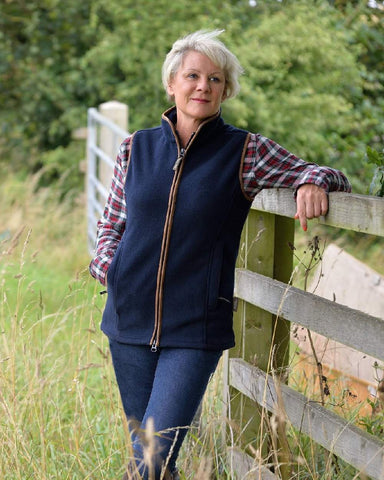 Woman wearing flannel shirt & fleece gilet outdoors in the fields