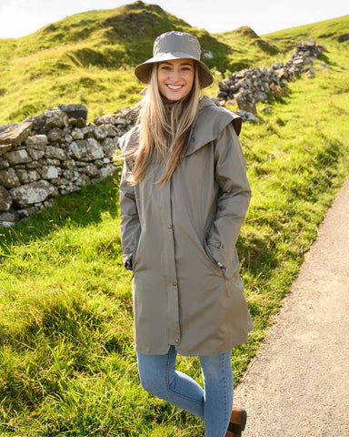 Woman wearing long waterproof coat and waterproof hat on a walk in the countryside