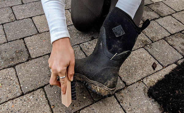 Person Scraping Off Muck From Their Wellies