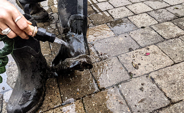 Person rinsing their wellies with clean water