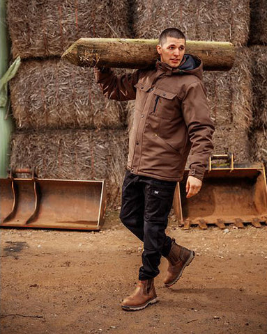 Man wearing farm boots while carrying wood on a farm