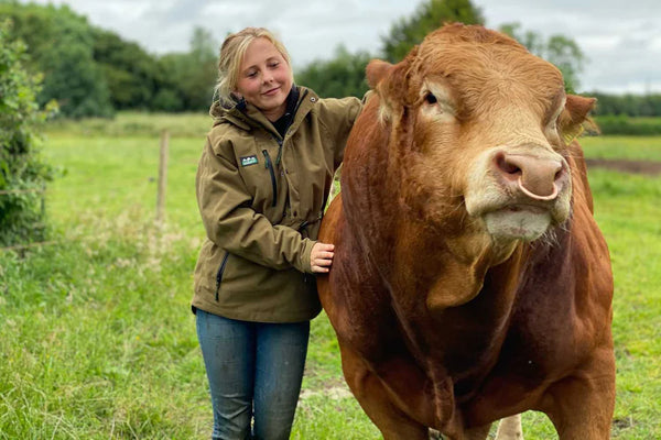 Girl wearing Ridgeline Smock standing next to cow in the countryside
