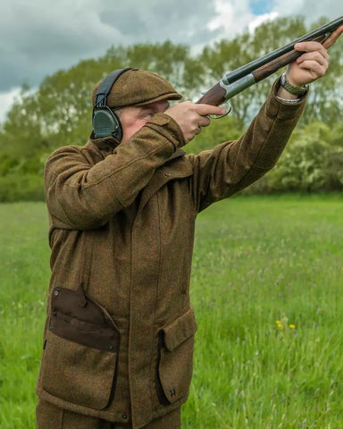 Man wearing Harkila Stornoway Tweed Shooting Jacket in terragon brown while shooting in a field