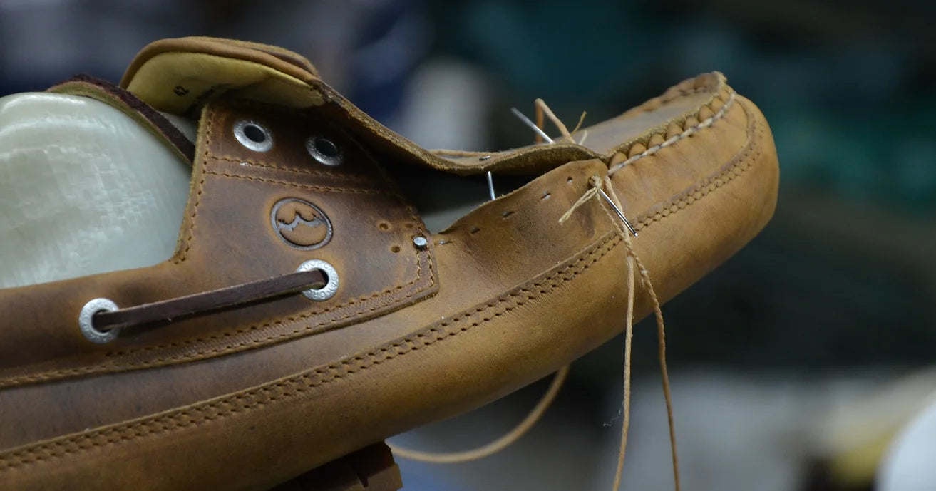 Close up of Orca Bay shoes in brown leather being stitched by hand