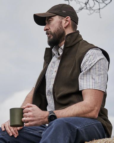 Man sitting down outdoors with a mug wearing Hoggs of Fife Kessock Tattersall Short Sleeved Shirt