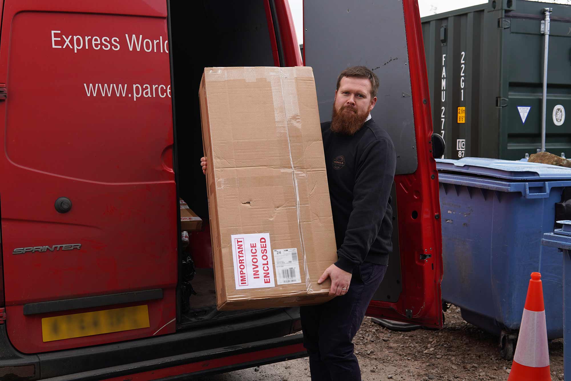 Matt Holland moving a large box from a Royal Mail van.