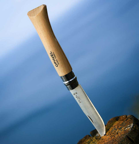 Opinel Classic Originals Knife with the tip in a wooden log against a blue background