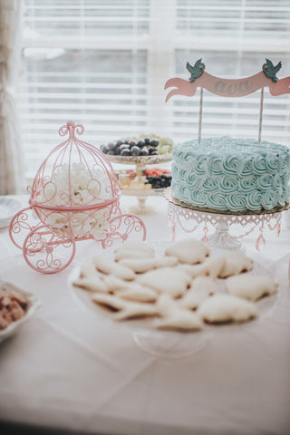 Cinderella-themed toddler birthday party table with a pumpkin carriage centerpiece and pale blue birthday cake.