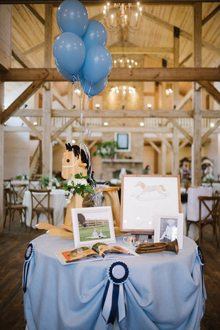 Styled table with rocking horse and images for a derby-themed 2nd birthday party.