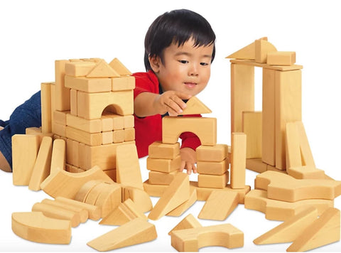 A toddler boy builds a structure with wooden blocks